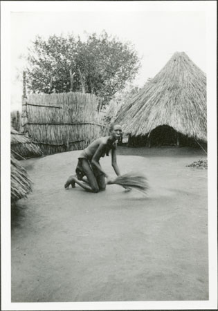 Anuak woman sweeping compound