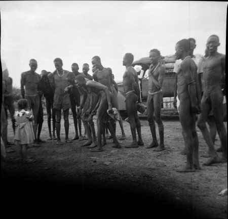 Girl showing Dinka men a doll