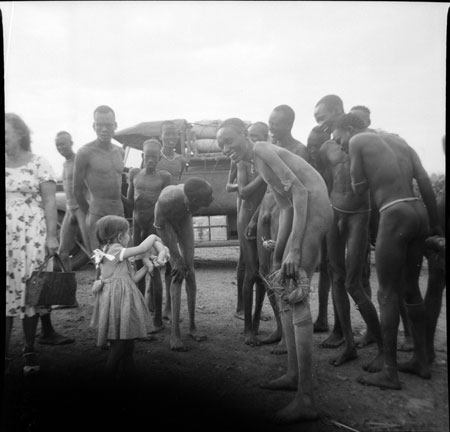 Girl showing Dinka men a doll