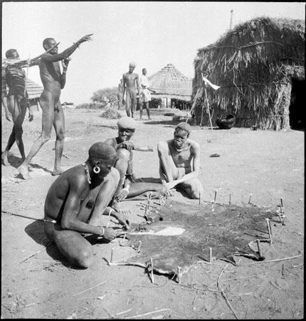 Dinka men preparing a skin