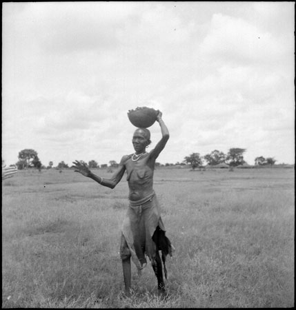 Dinka woman carrying vessel