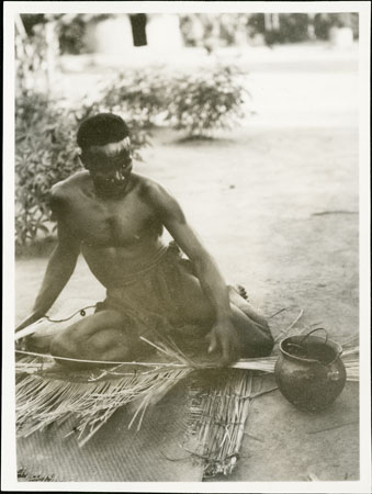 Zande man weaving shield