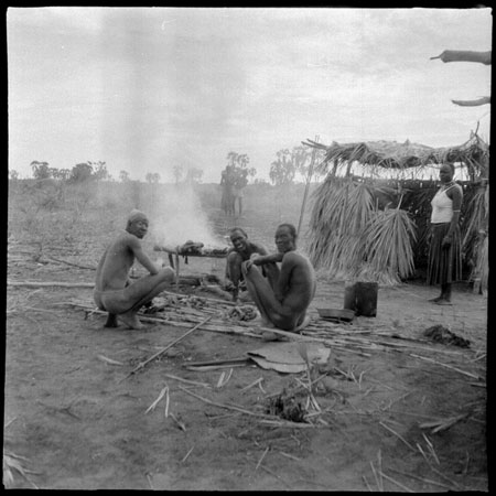 Mandari men preparing meat