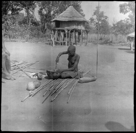 Mandari woman decorating gourd vessel